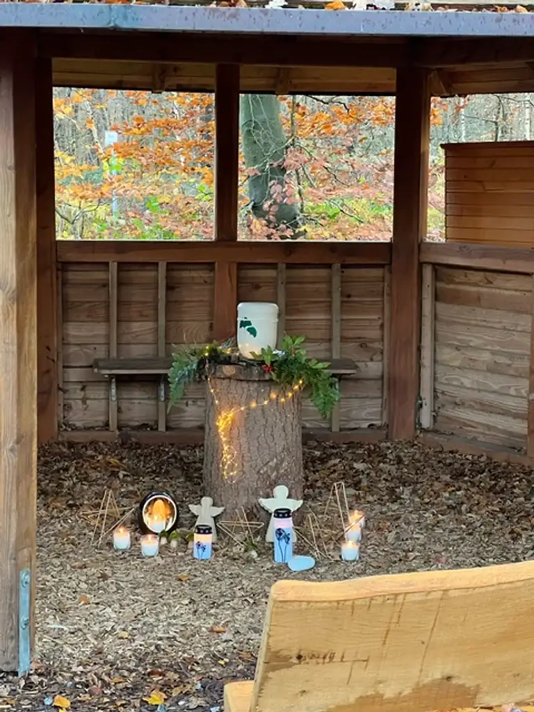 Andachtsplatz im FriedWald mit Urne, Kerzen und herbstlich gefärbtem Wald
