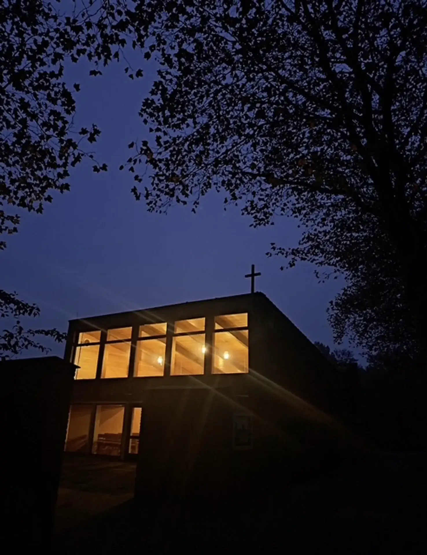 Warm erleuchtete Friedhofskapelle in der Abenddämmerung