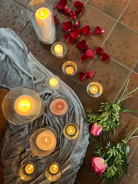 Brennende Kerzen mit roten Rosenblättern als Teil eines Kerzenrituals