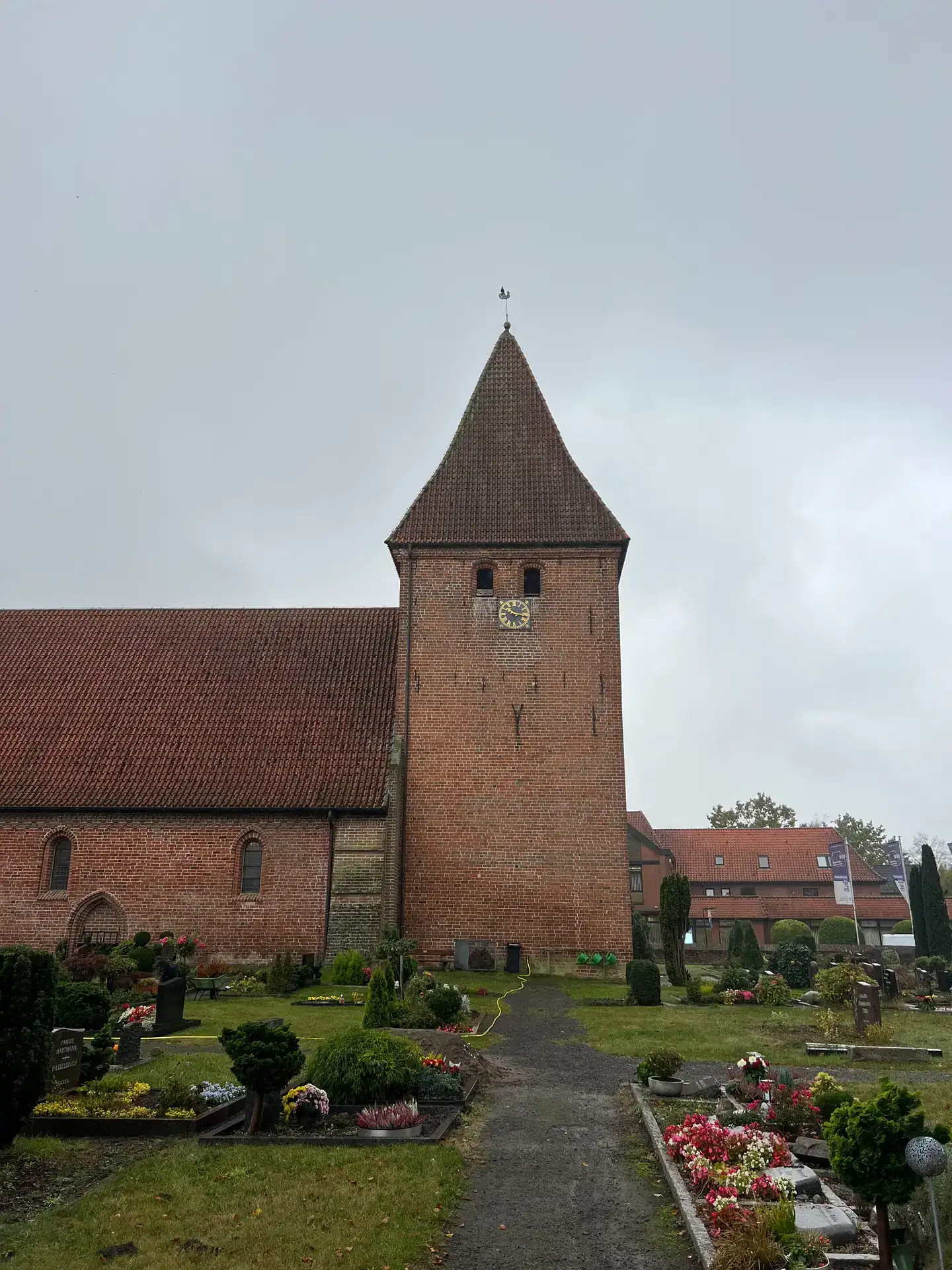 Backsteinkirche mit Turm und angrenzendem Friedhof