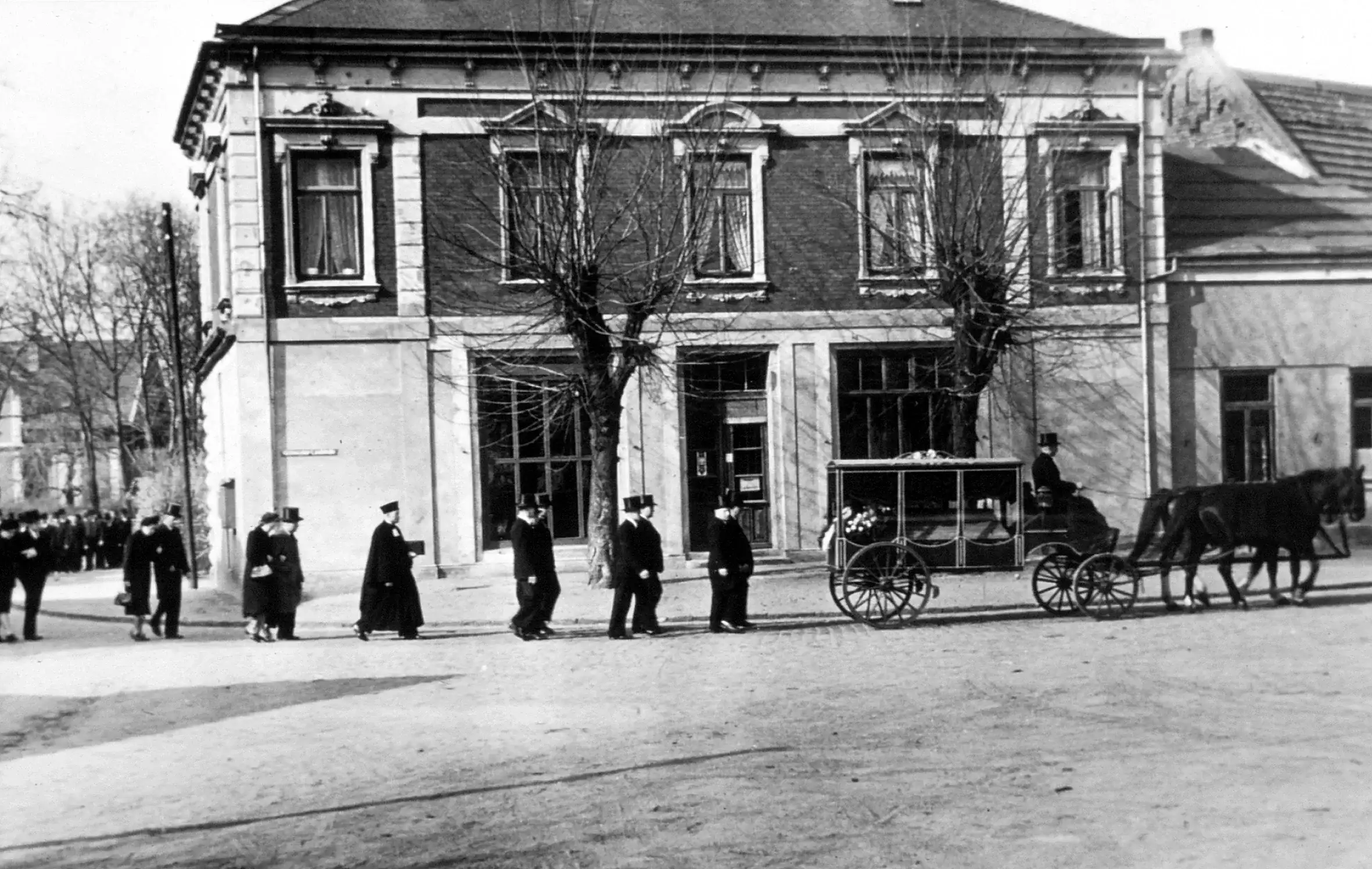 Historische Aufnahme: Trauerzug mit Pferdewagen vor dem Geschäftshaus