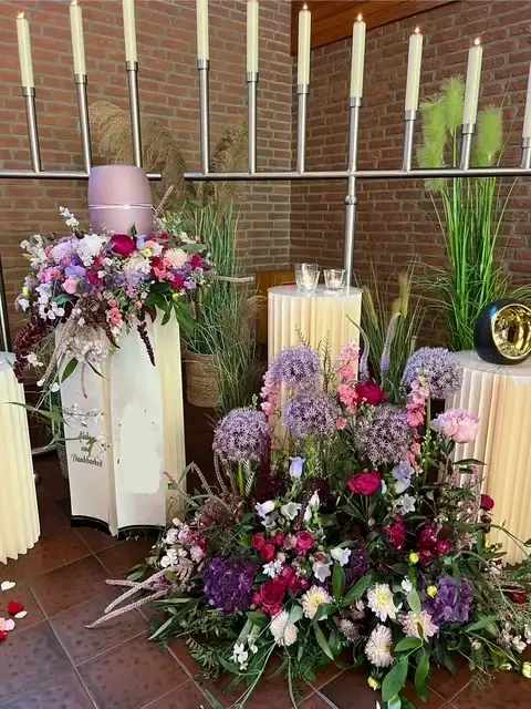 Urne auf einer Säule mit sommerlichem Blumenschmuck in der Trauerhalle